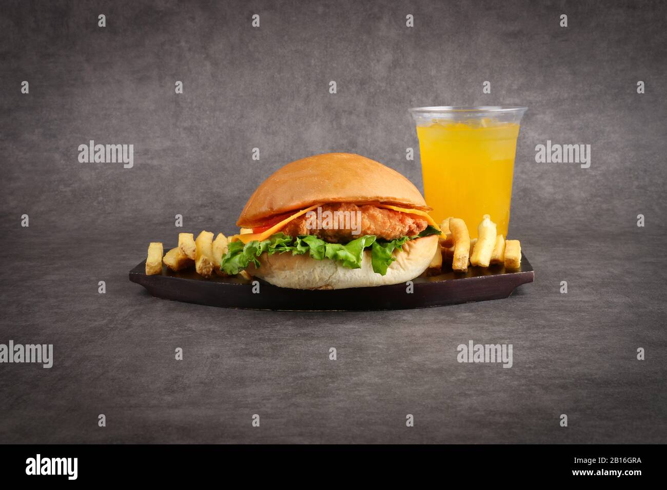 hamburger di pollo croccante e patatine fritte e succo d'arancia su sfondo grigio - pasto per bambini - cena Foto Stock