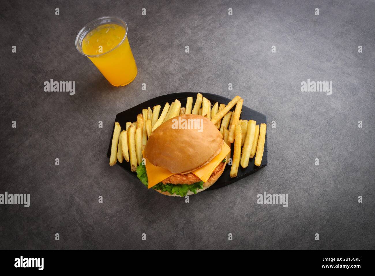 hamburger di pollo croccante e patatine fritte e succo d'arancia su sfondo grigio - pasto per bambini - cena Foto Stock