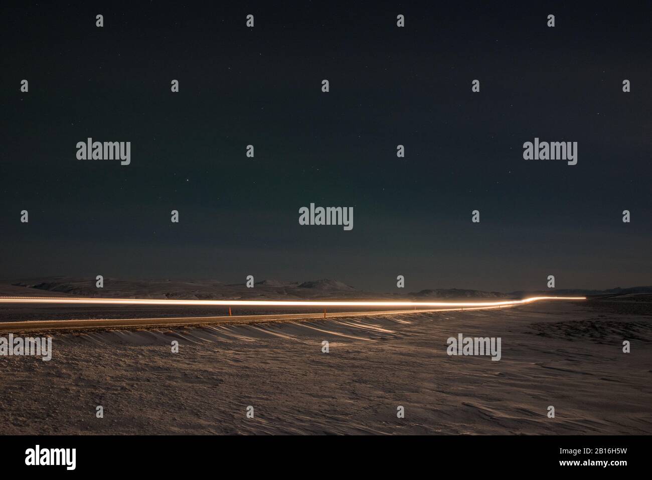 Auto percorsi luce di notte su una strada in Islanda Foto Stock