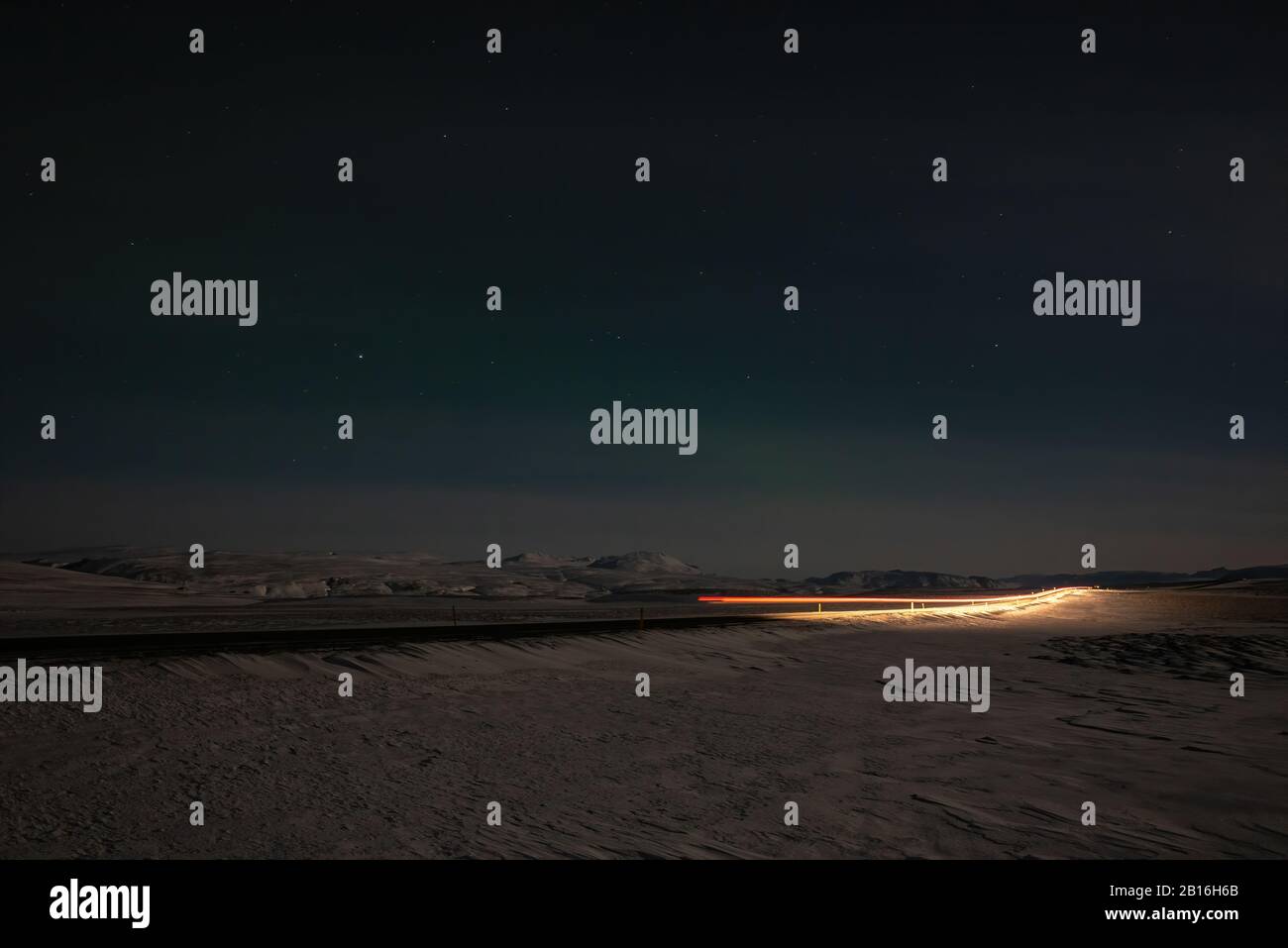 Auto percorsi luce di notte su una strada in Islanda Foto Stock