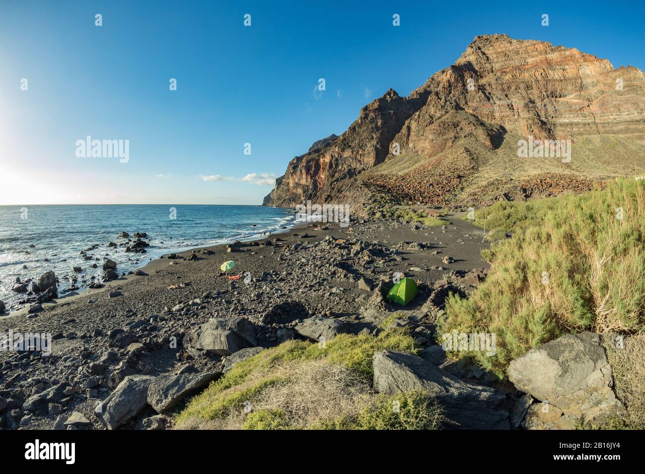 Spiaggia di Playa del ingles con sabbia nera vulcanica sull'oceano atlantico a la Gomera. Un popolare luogo di vacanza per turisti e locali. Valle Gran Rey, C. Foto Stock