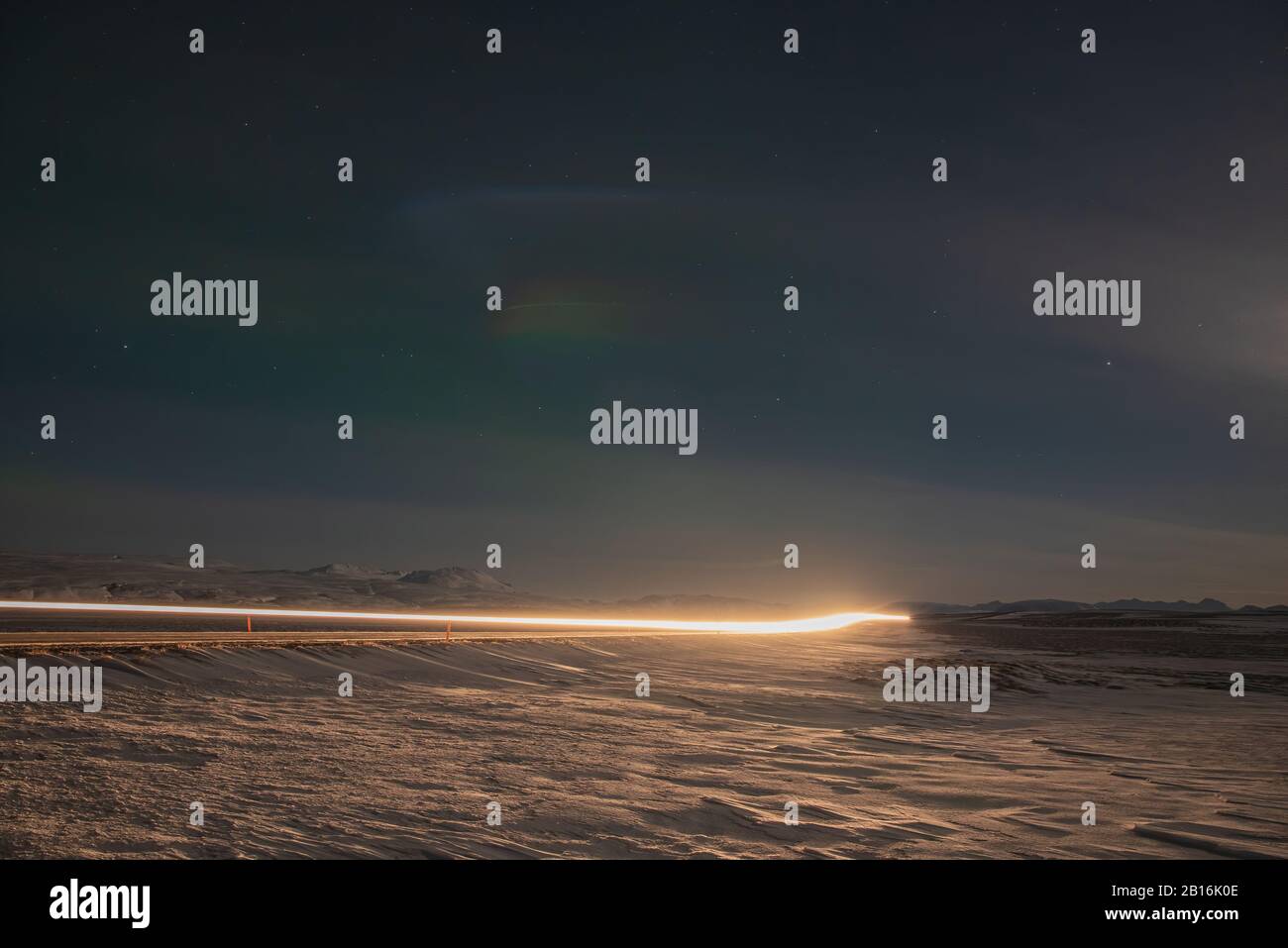 Auto percorsi luce di notte su una strada in Islanda Foto Stock