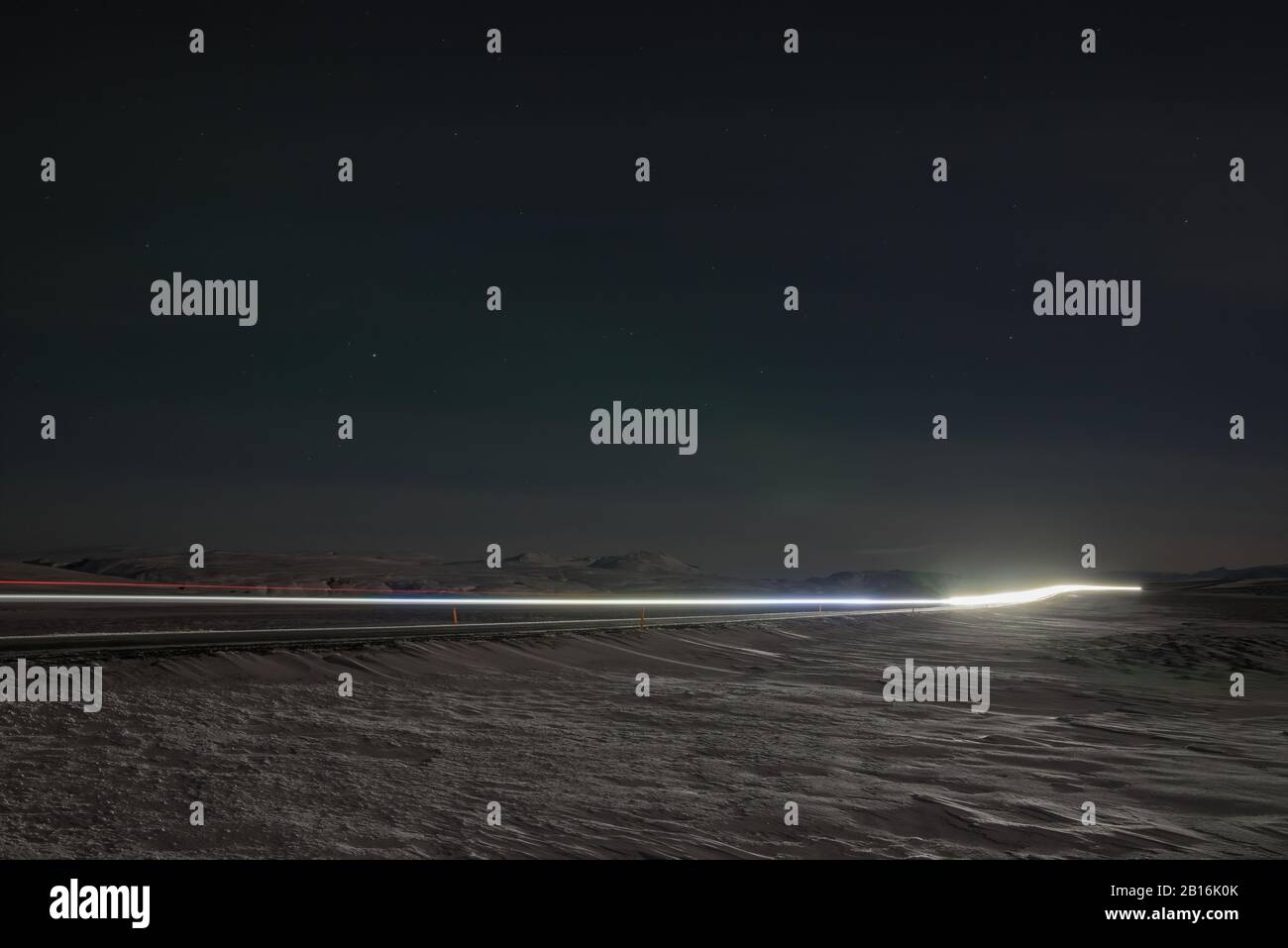 Auto percorsi luce di notte su una strada in Islanda Foto Stock