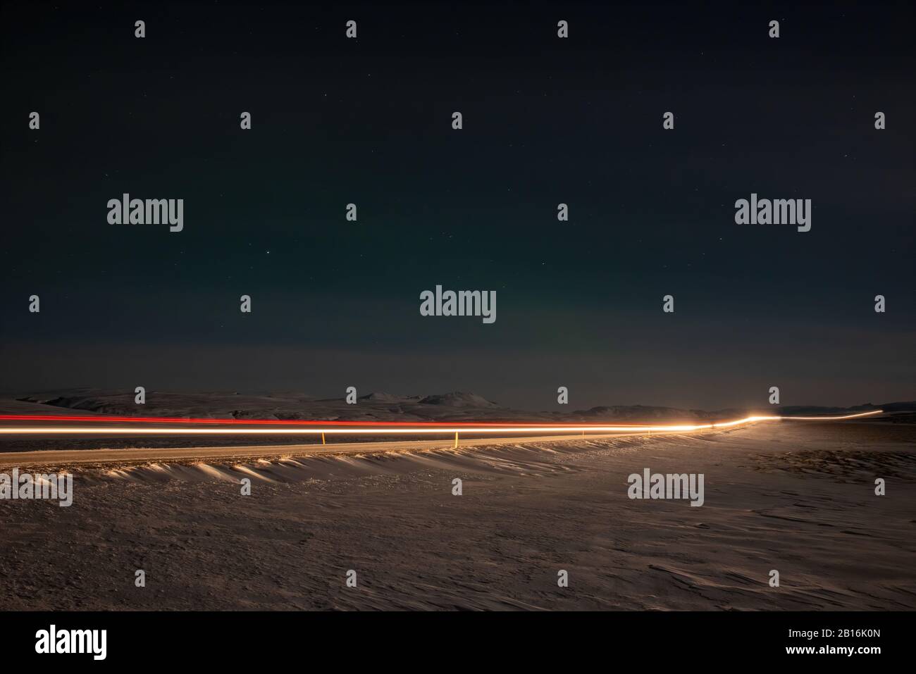 Auto percorsi luce di notte su una strada in Islanda Foto Stock