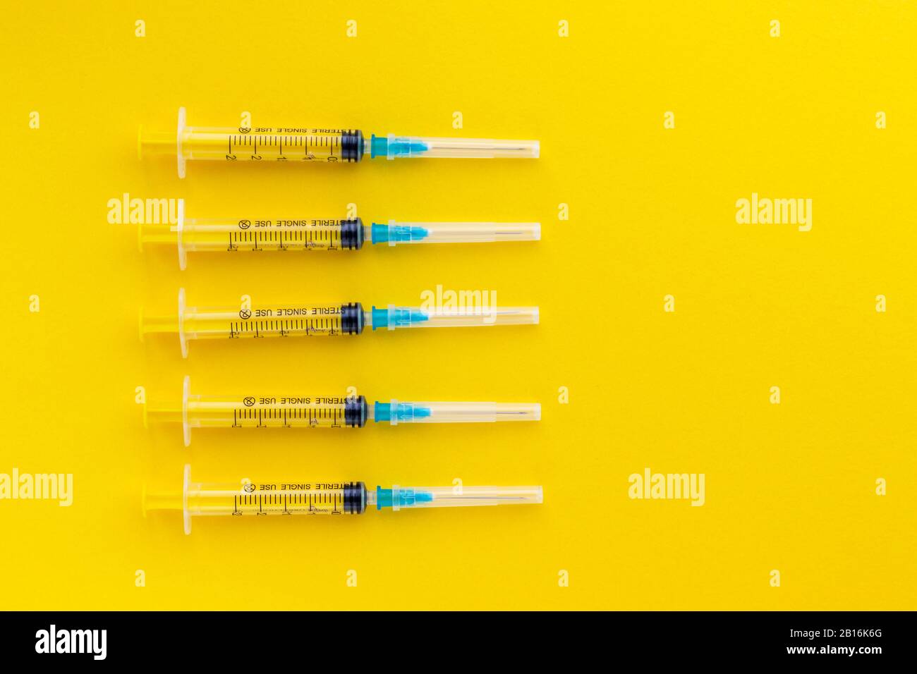 Siringhe monouso su sfondo giallo brillante. Vaccinazione contro l'influenza e il coronavirus. Concetto di assistenza sanitaria. Iniezione medica. Ago, dosaggio Foto Stock