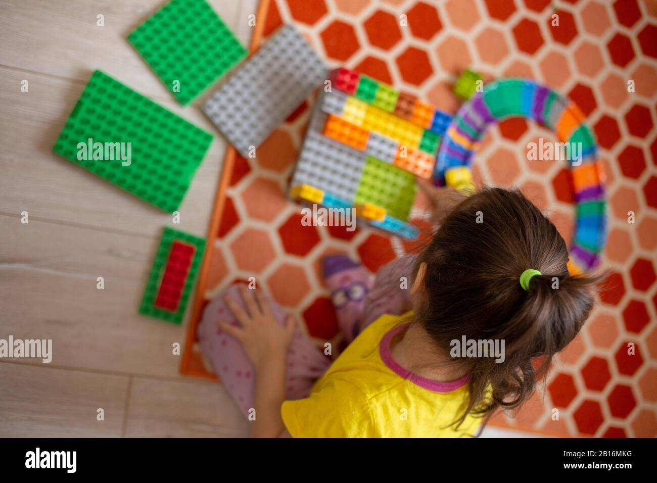 Costruttore di plastica multicolore nelle mani della ragazza. Giochi educativi per bambini. Interni domestici Foto Stock