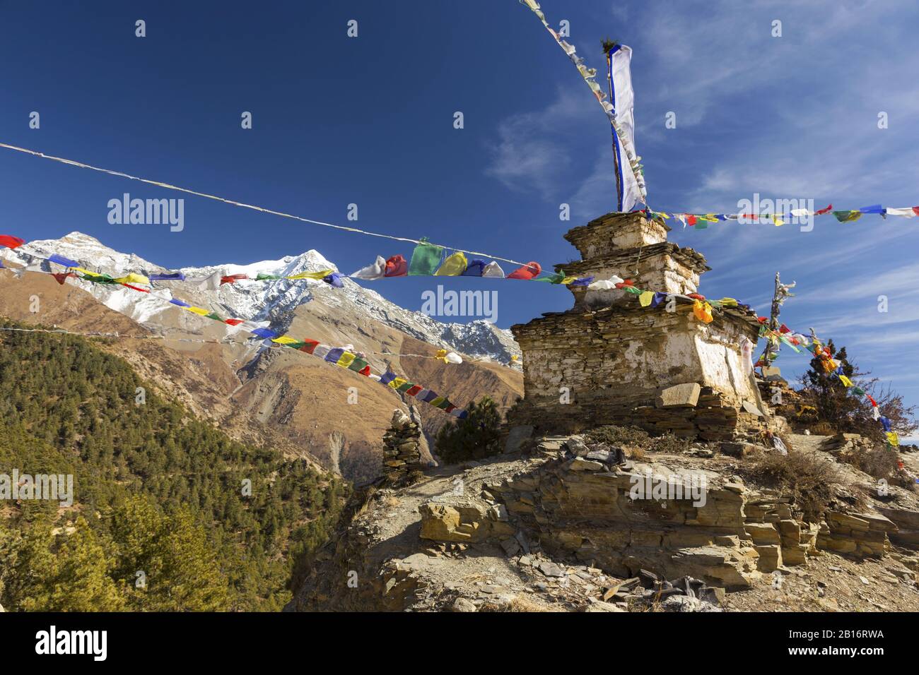 Monumento Alla Pietra Buddista Con Bandiere Di Preghiera E Il Paesaggio Delle Cime Innevate Della Montagna. Trekking Sul Circuito Di Annapurna, Nepal Himalaya Mountains Foto Stock