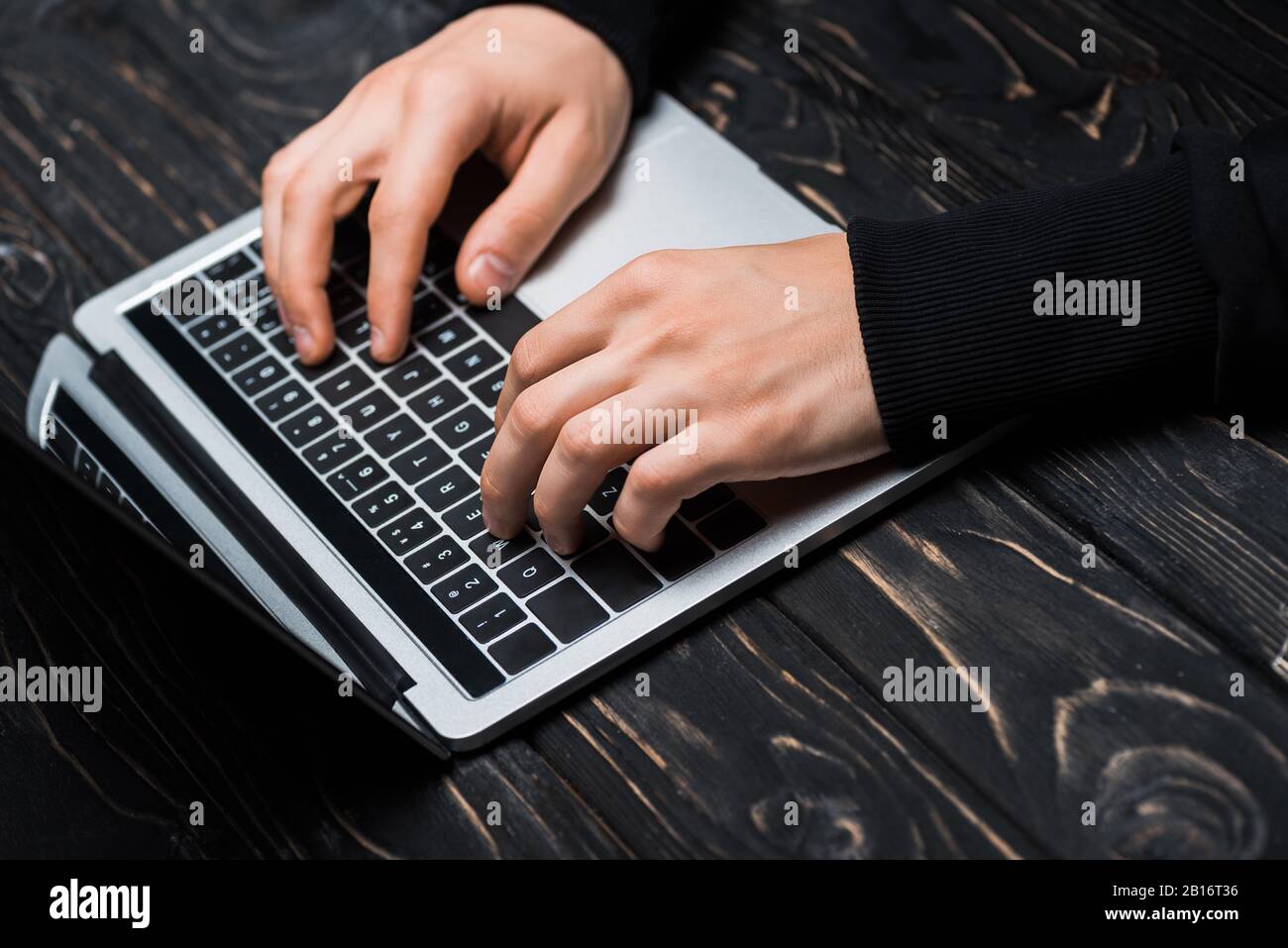 vista ritagliata della digitazione hacker sulla tastiera del computer portatile Foto Stock