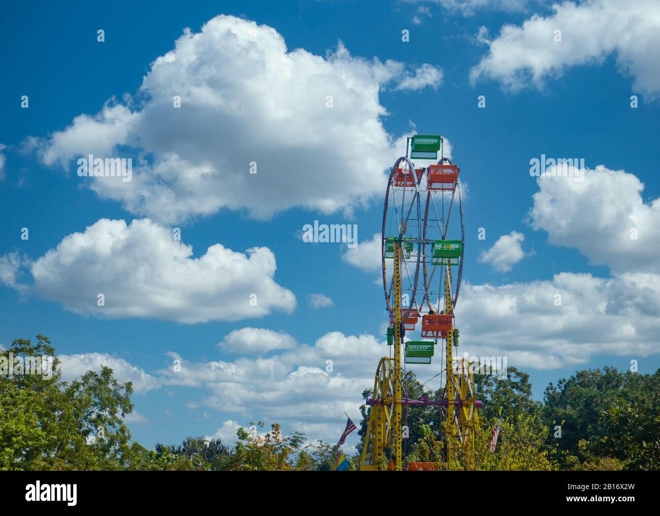 Giallo Rosso e Verde Ferris ruota fuori Dagli Alberi Foto Stock