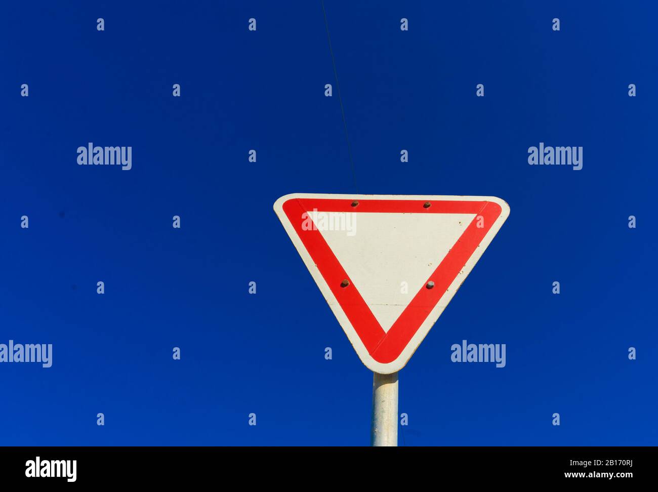 Segnale stradale contro un cielo blu profondo, composizione minimalista che simboleggia prudenza, priorità e processo decisionale Foto Stock
