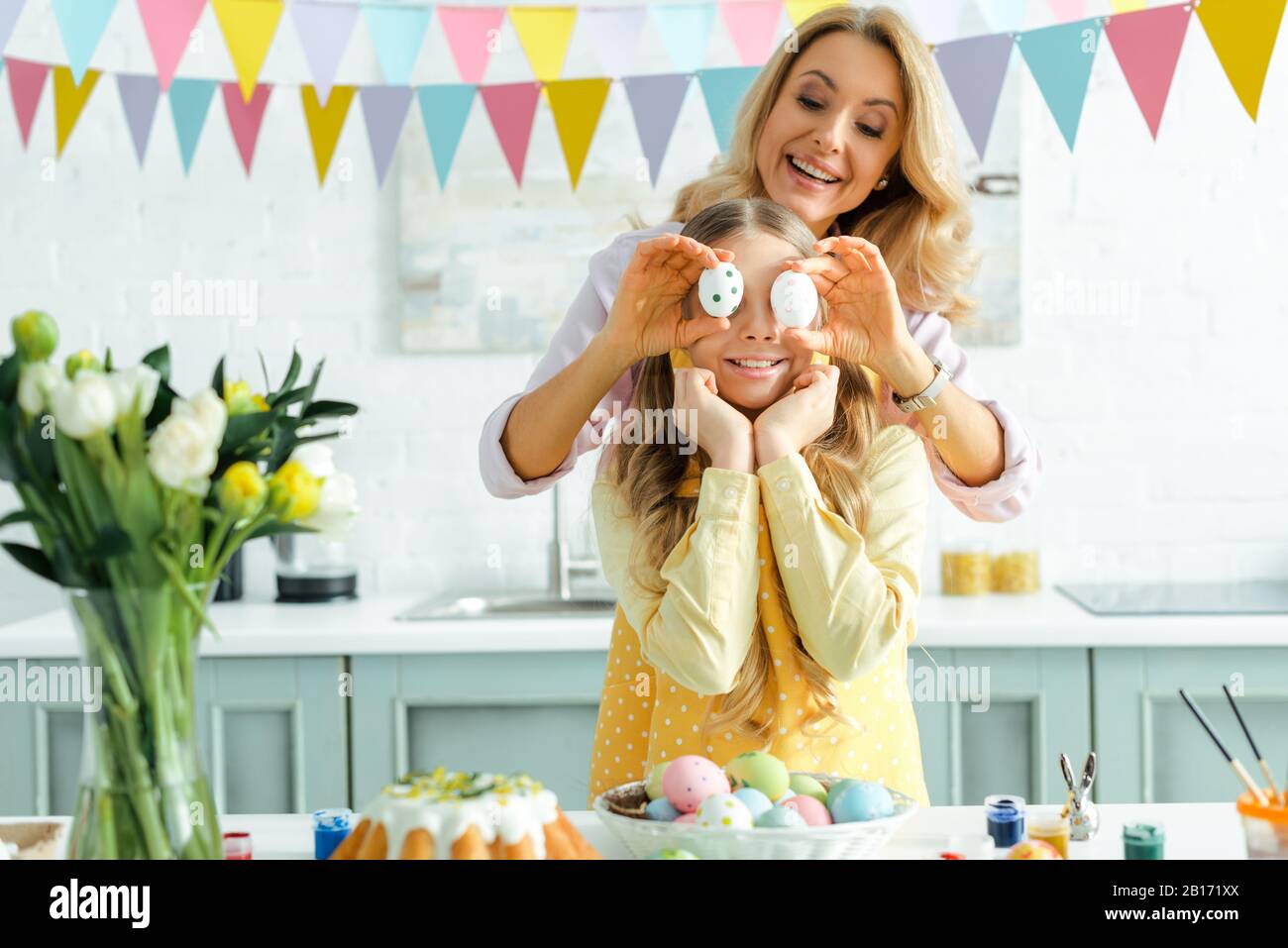 madre felice che copre gli occhi di figlia con uova di pasqua dipinte Foto Stock