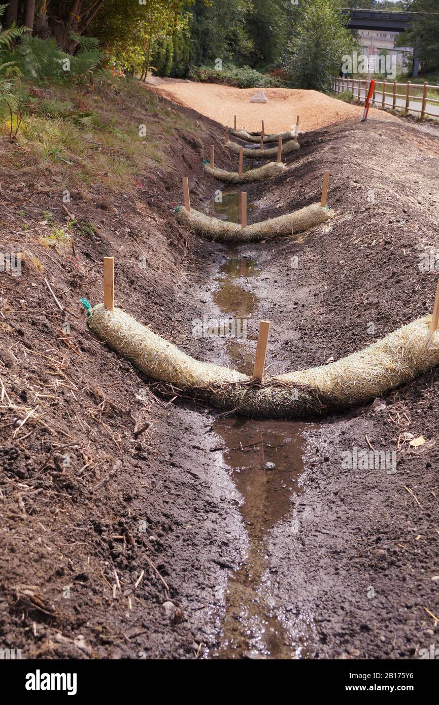 Lavori di drenaggio di terra. L'uso di wattles di paglia (vermi di paglia, bio-tronchi, tagliatelle di paglia). Foto Stock