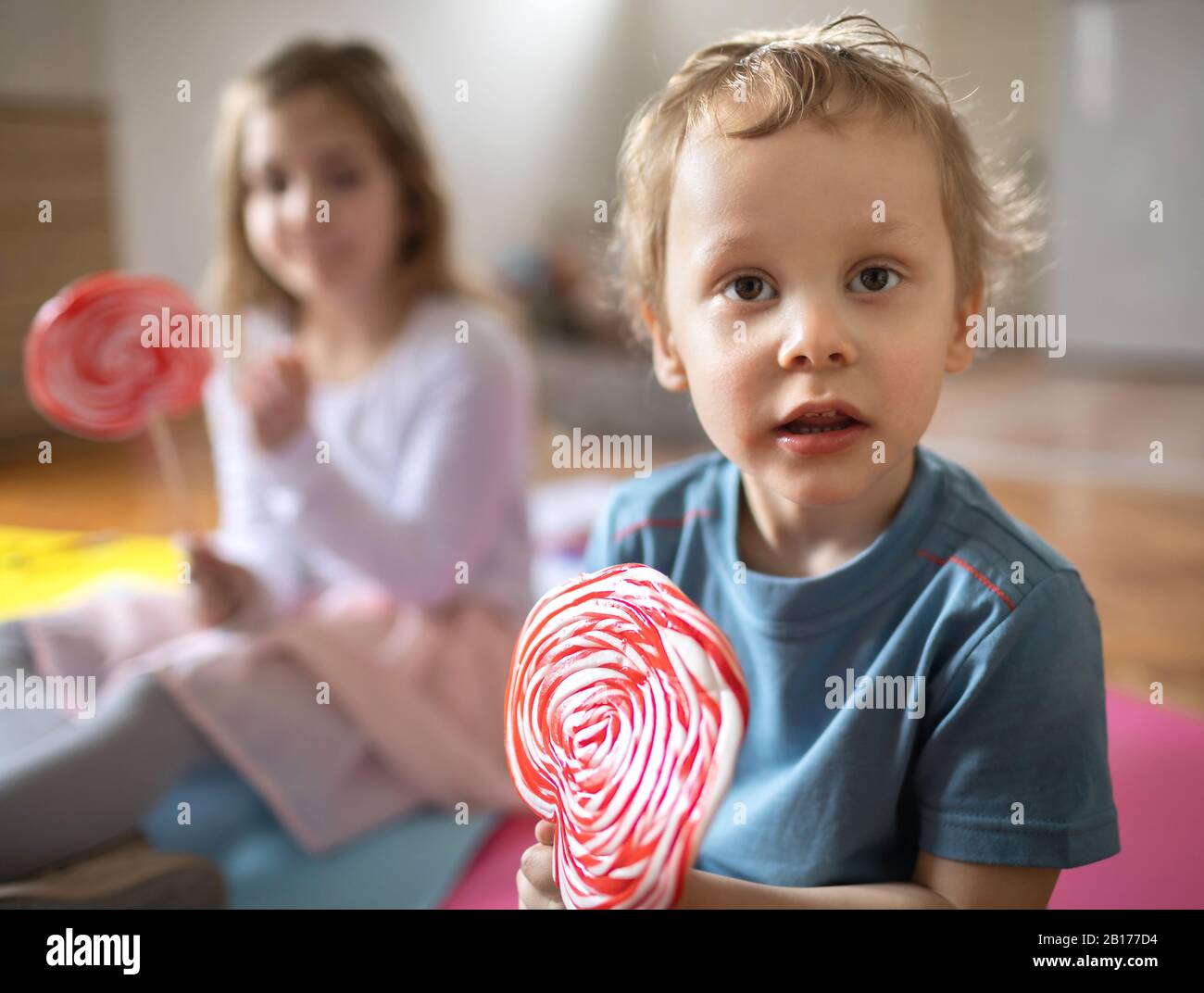 Due bambini giocano e mangiano lecca-lecca Foto Stock