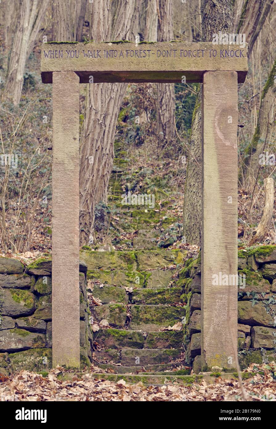 Vecchia struttura di porta in pietra nel mezzo del bosco. Sull'architrave è scritto 'Quando si cammina in una foresta, non dimenticare di bussare'. Foto Stock