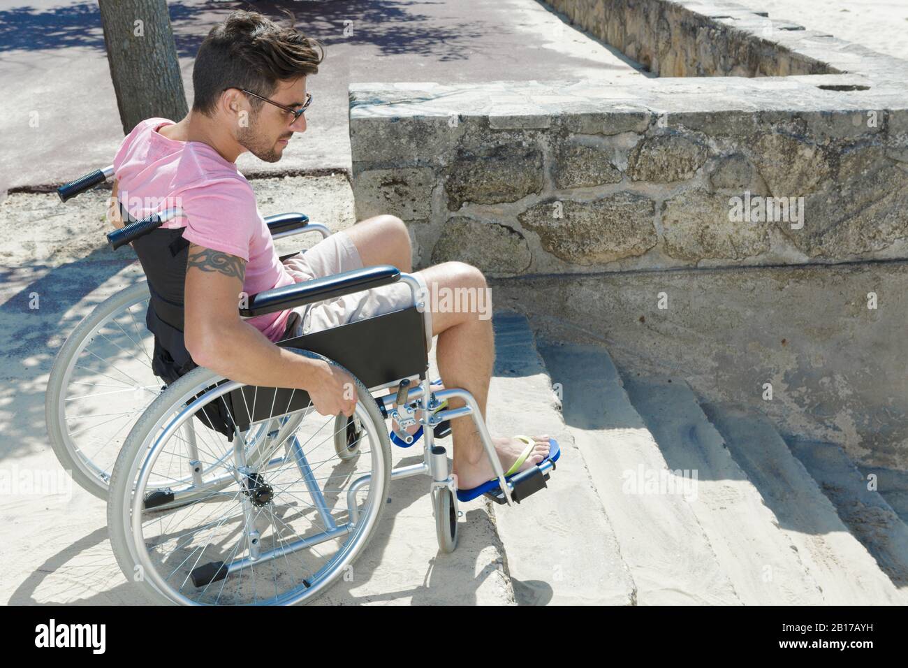 uomo in carrozzina che cerca di trovare la soluzione per le scale Foto Stock