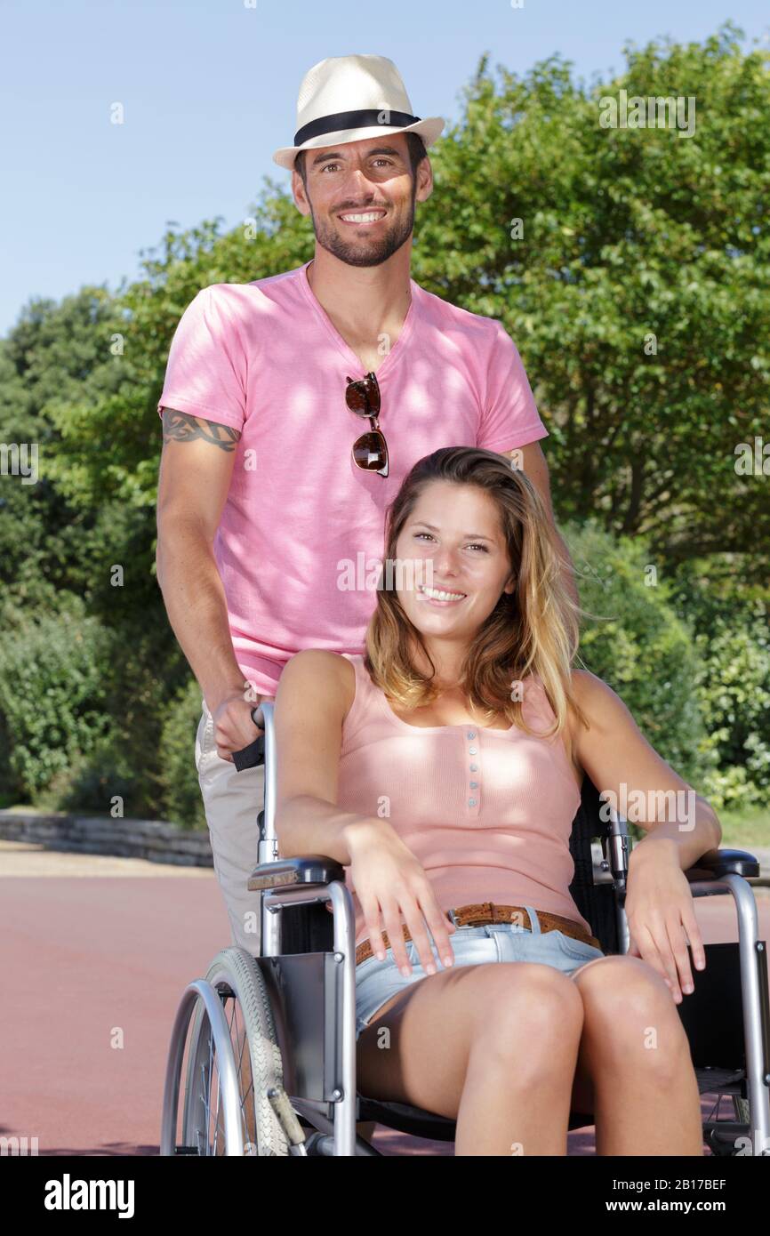 donna in sedia a rotelle con un buon uomo nel parco Foto Stock