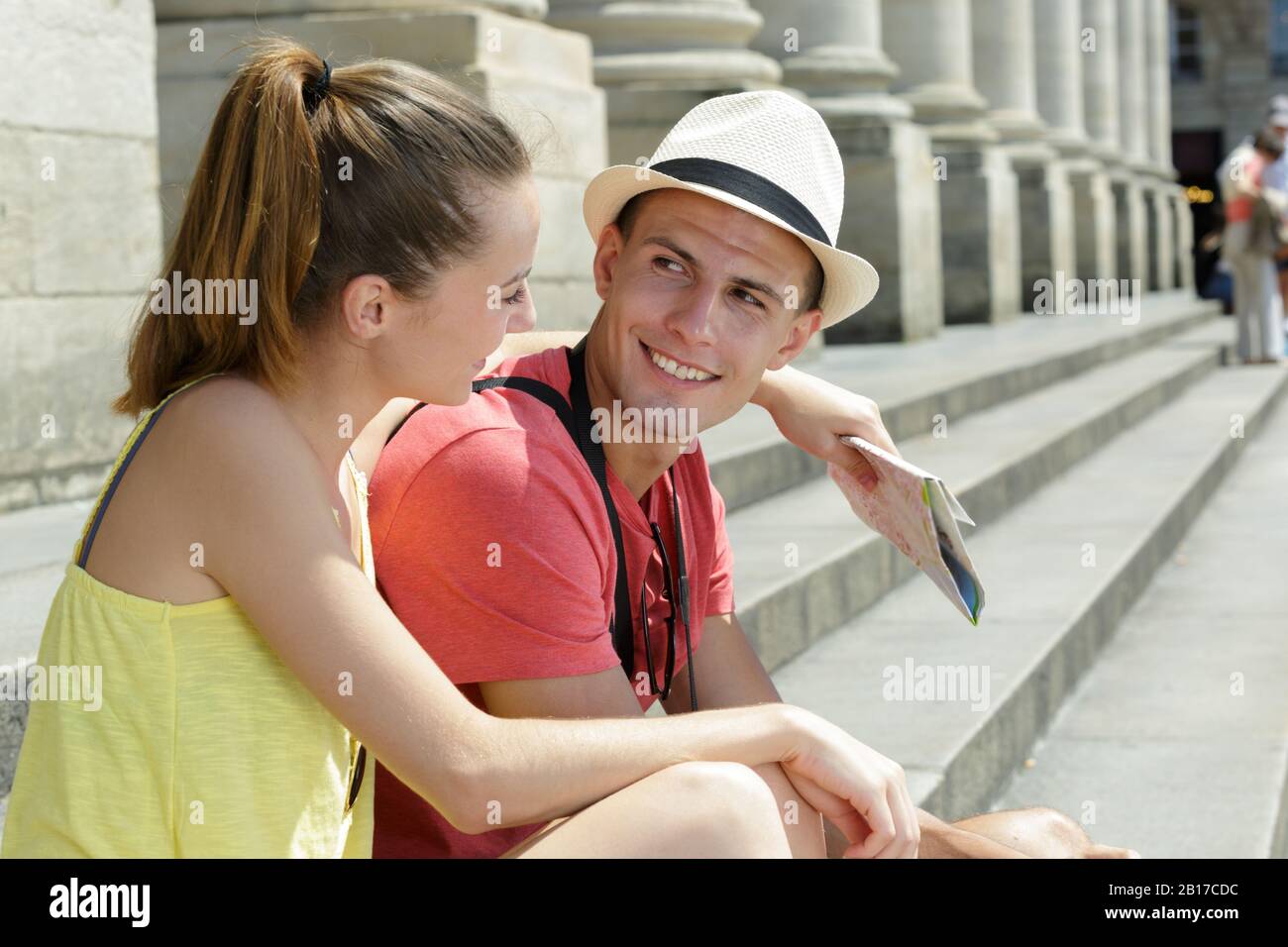 giovani vacanzieri seduti su gradini di un edificio che tiene la mappa Foto Stock