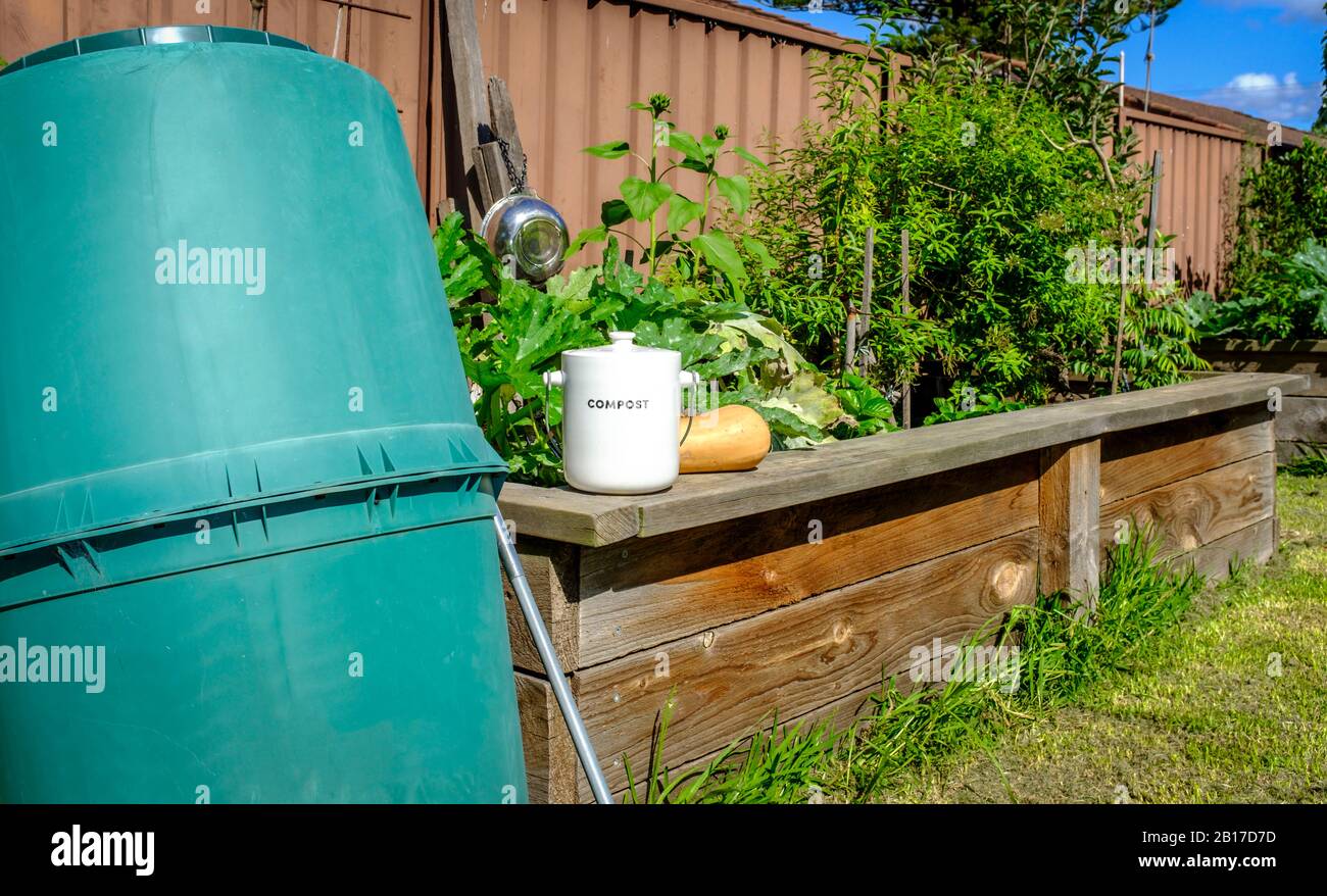 Vaso di raccolta rifiuti della cucina all'esterno sulla parete del letto vegetale rialzato vicino al bidone del composto, riciclando rifiuti domestici della cucina organica in composto Foto Stock