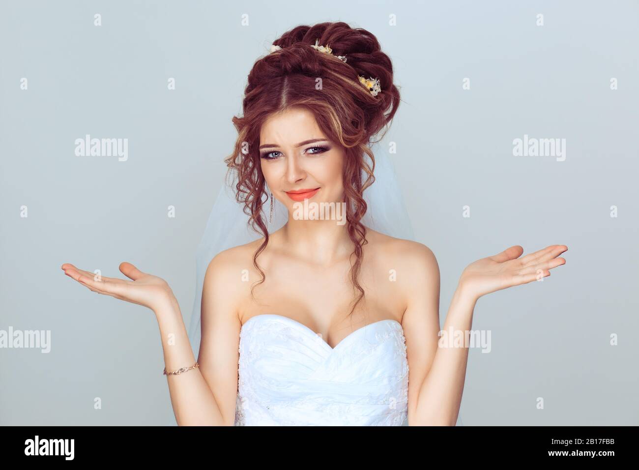 Le cose cattive accadono. Sposa ragazza gesturing con entrambe le mani confusione non so fare divertente perplesso faccia contro sfondo azzurro chiaro Foto Stock