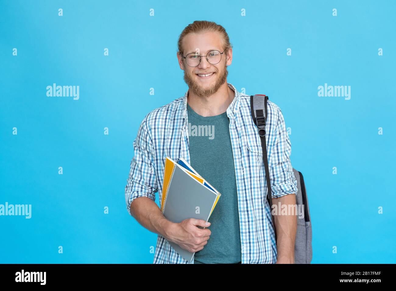 Ritratto studente universitario sorridente in occhiali in piedi tenere copybooks zaino Foto Stock