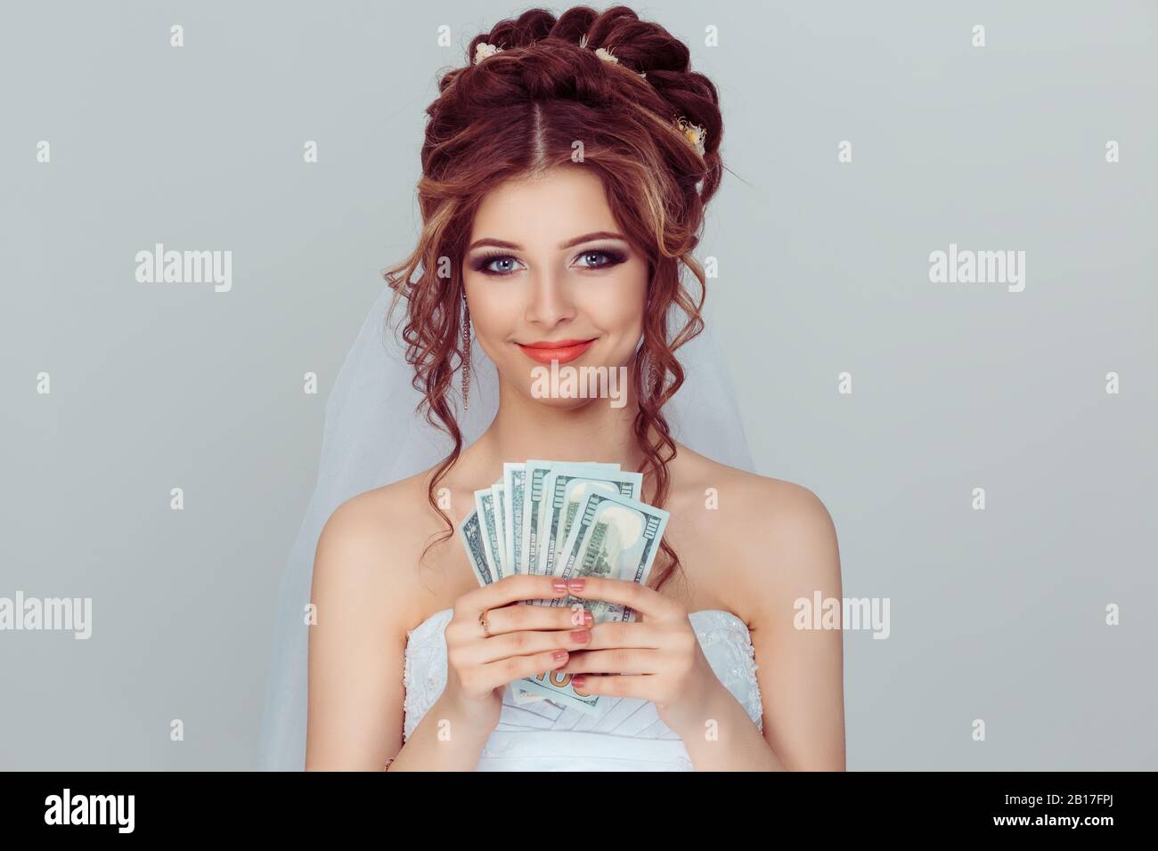 Sposa con denaro. Closeup ritratto bella giovane donna bella in abito da sposa ragazza guardando voi macchina fotografica tenendo soldi usd dollaro moneta luce Foto Stock