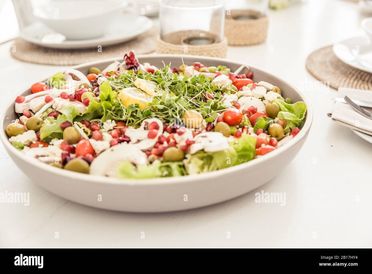 Ciotola di insalata mista con semi di melograno su tavola posata Foto Stock