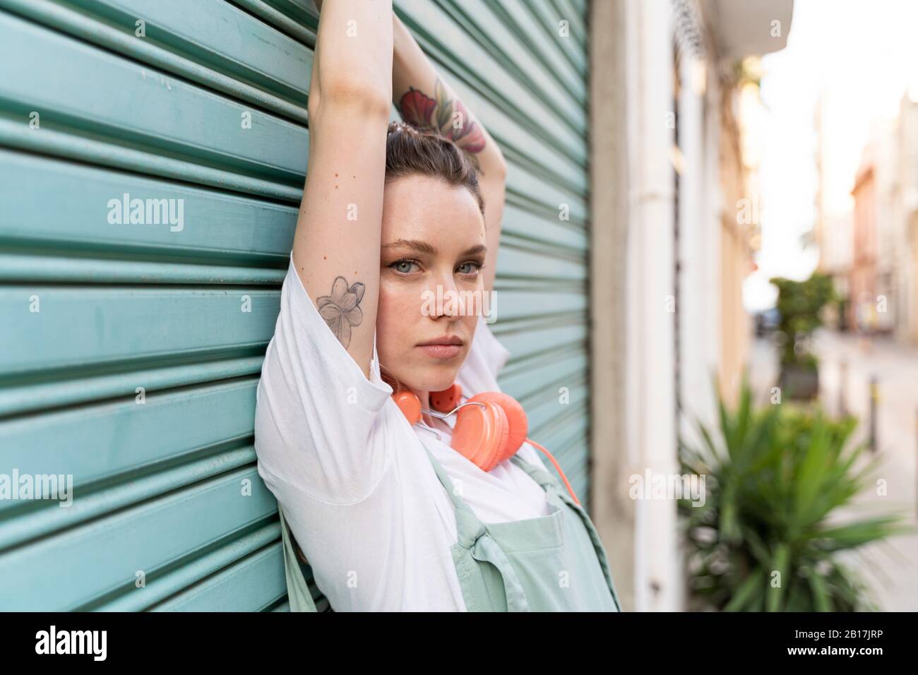 Ritratto di giovane donna con cuffie davanti al serranda blu Foto Stock