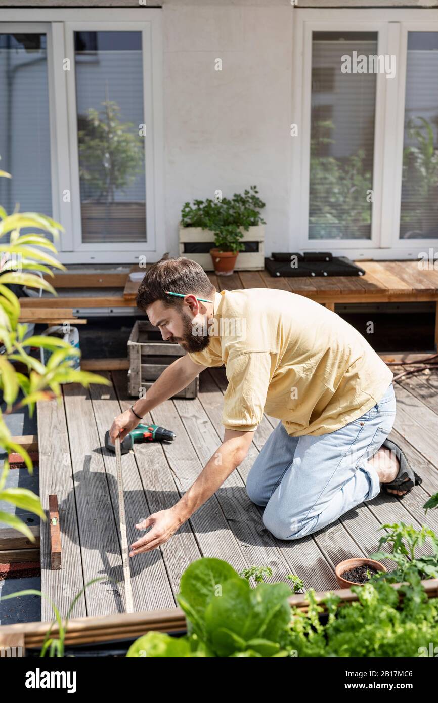 Giovane handyman costruire terrazza in legno di fronte alla sua casa Foto Stock