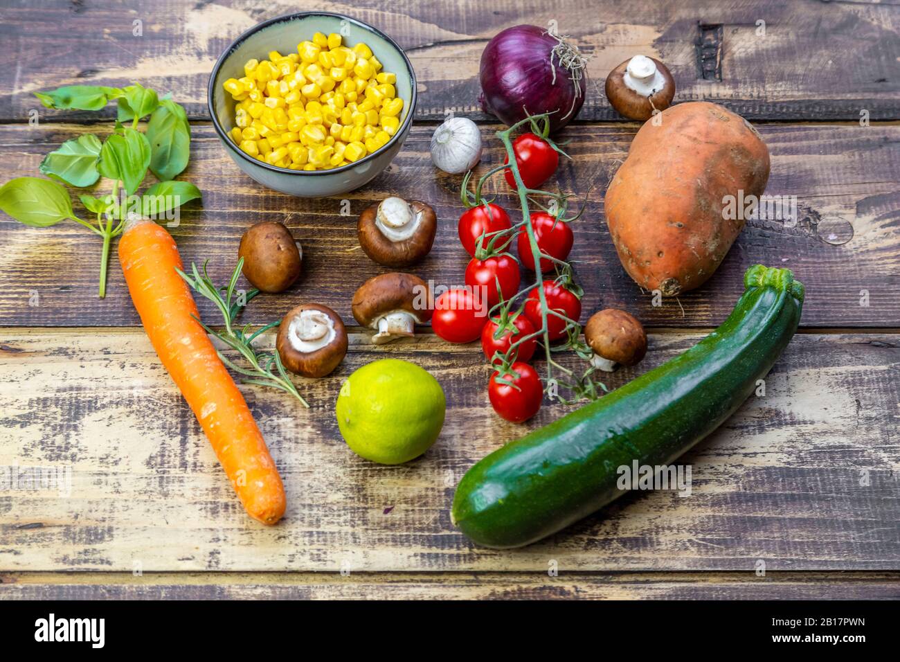 Ingredienti per curry di patate dolci (patate dolci, zucchine, funghi, mais, pomodori, cipolle, aglio, lime, basilico) Foto Stock