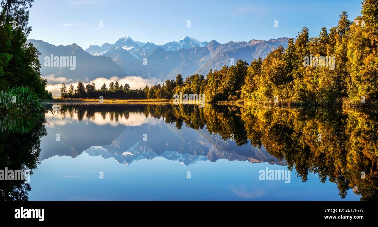 Nuova Zelanda, Westland District, Fox Glacier, Lake Matheson che riflette la foresta circostante e la catena montuosa distante Foto Stock