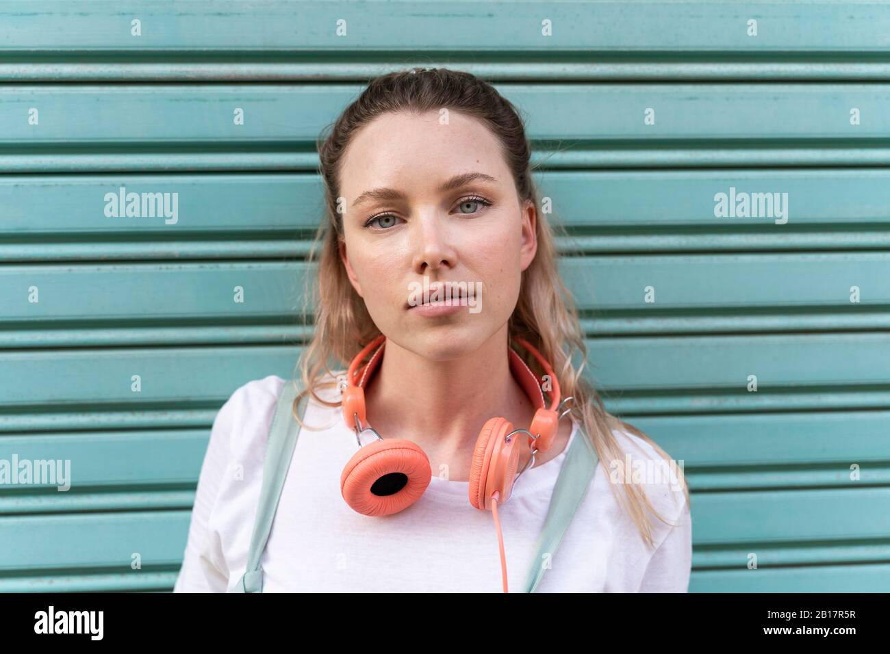Ritratto di giovane donna con cuffie davanti al serranda blu Foto Stock