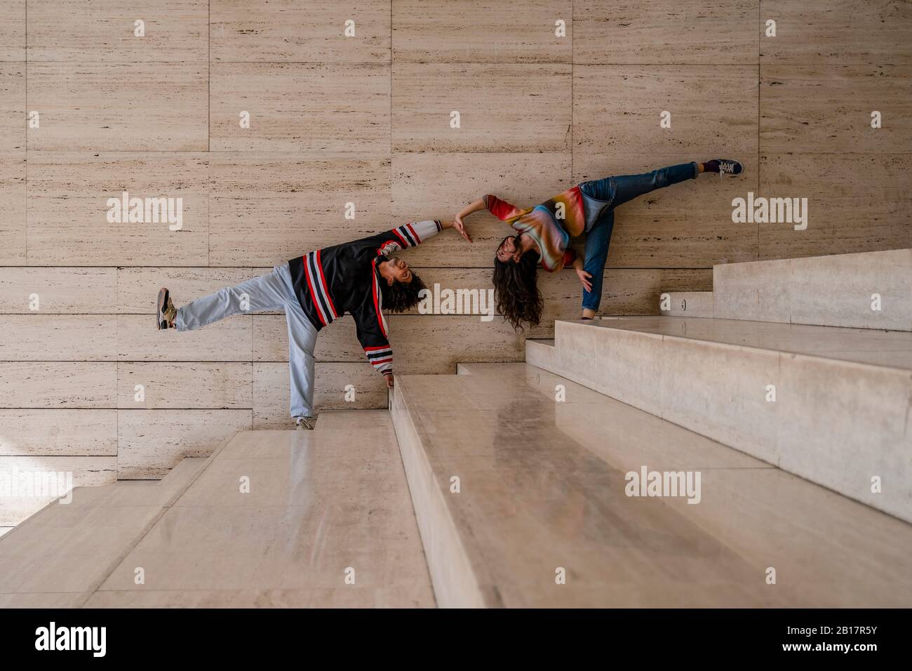 Coppia di ballerini su un muro, sollevando le gambe Foto Stock