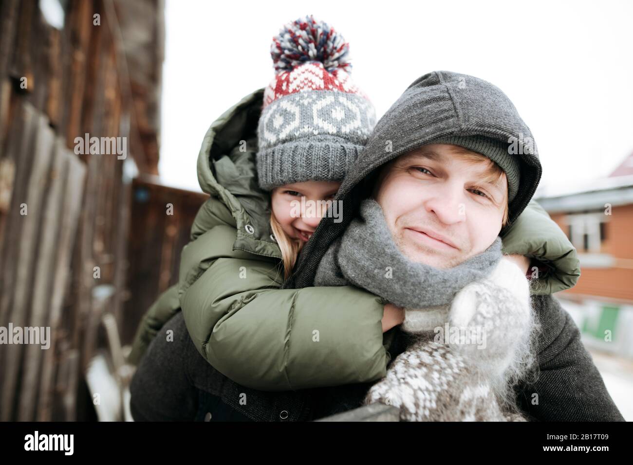 Ritratto di padre che porta figlia piggyback all'aperto in inverno Foto Stock