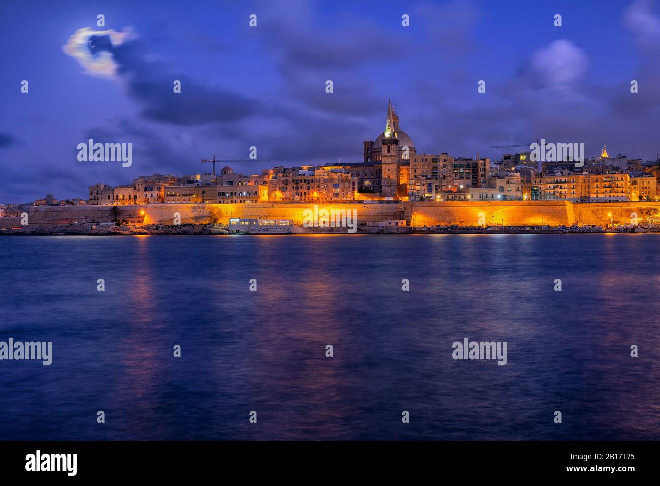 Malta, Valletta, vista della città illuminata di notte attraverso l'acqua Foto Stock