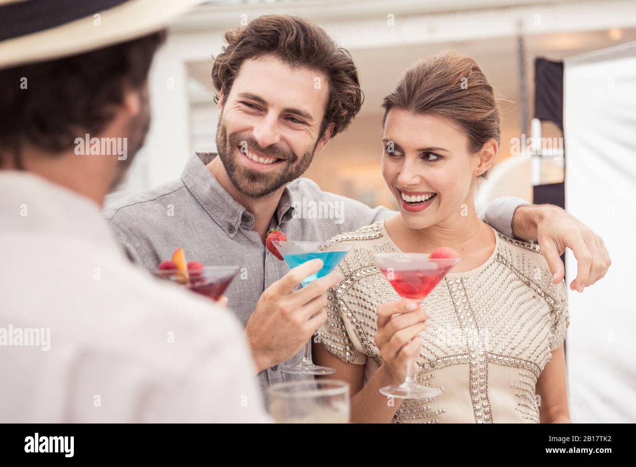 Coppia e amico socializzano in un cocktail party Foto Stock