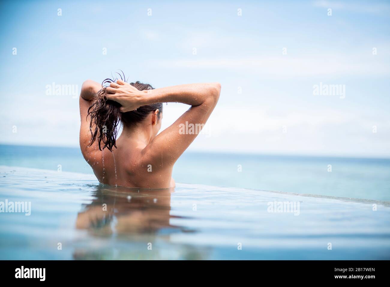 Vista posteriore della donna in piscina a sfioro, Isola di Maguhdhuvaa, Atollo di Gaafu Dhalu, Maldive Foto Stock