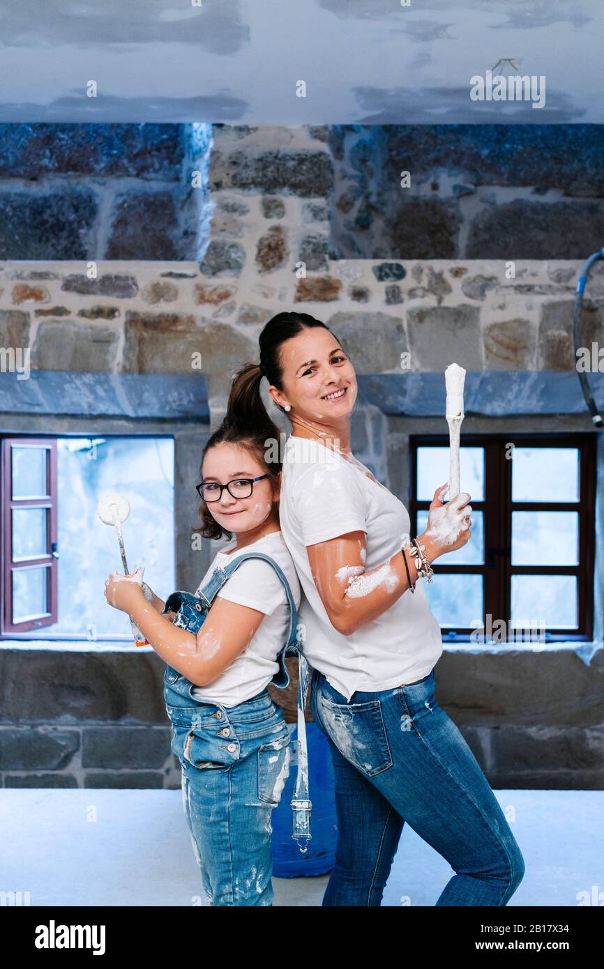 Ritratto di madre e figlia che posano con pennello e rullo di vernice Foto Stock