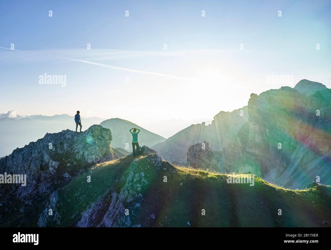 Escursionisti in piedi su sperone di roccia, guardando le montagne Foto Stock