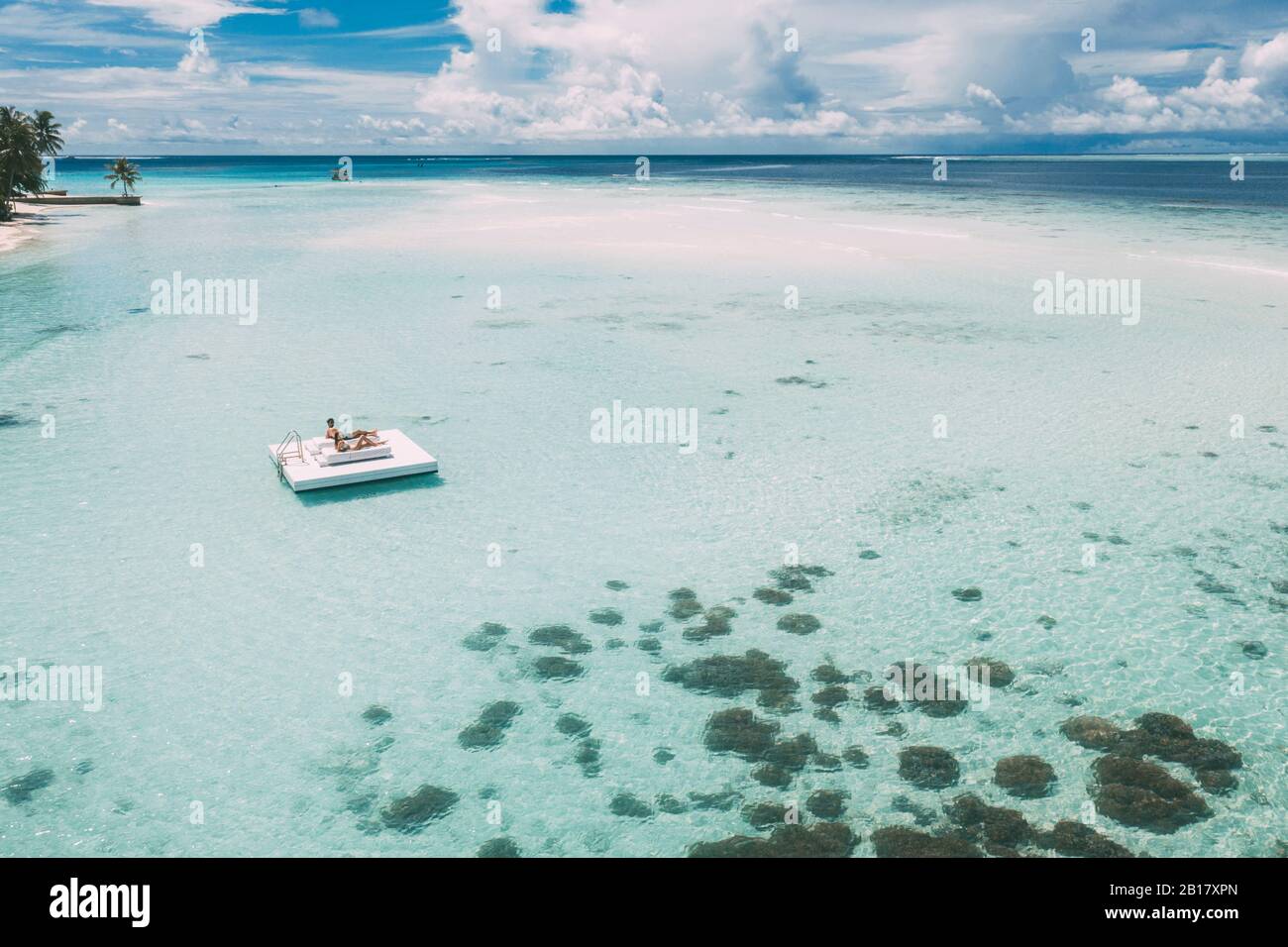 Coppia sdraiata su una piattaforma nel mare, Isola di Maguhdhuvaa, Atollo di Gaafu Dhalu, Maldive Foto Stock