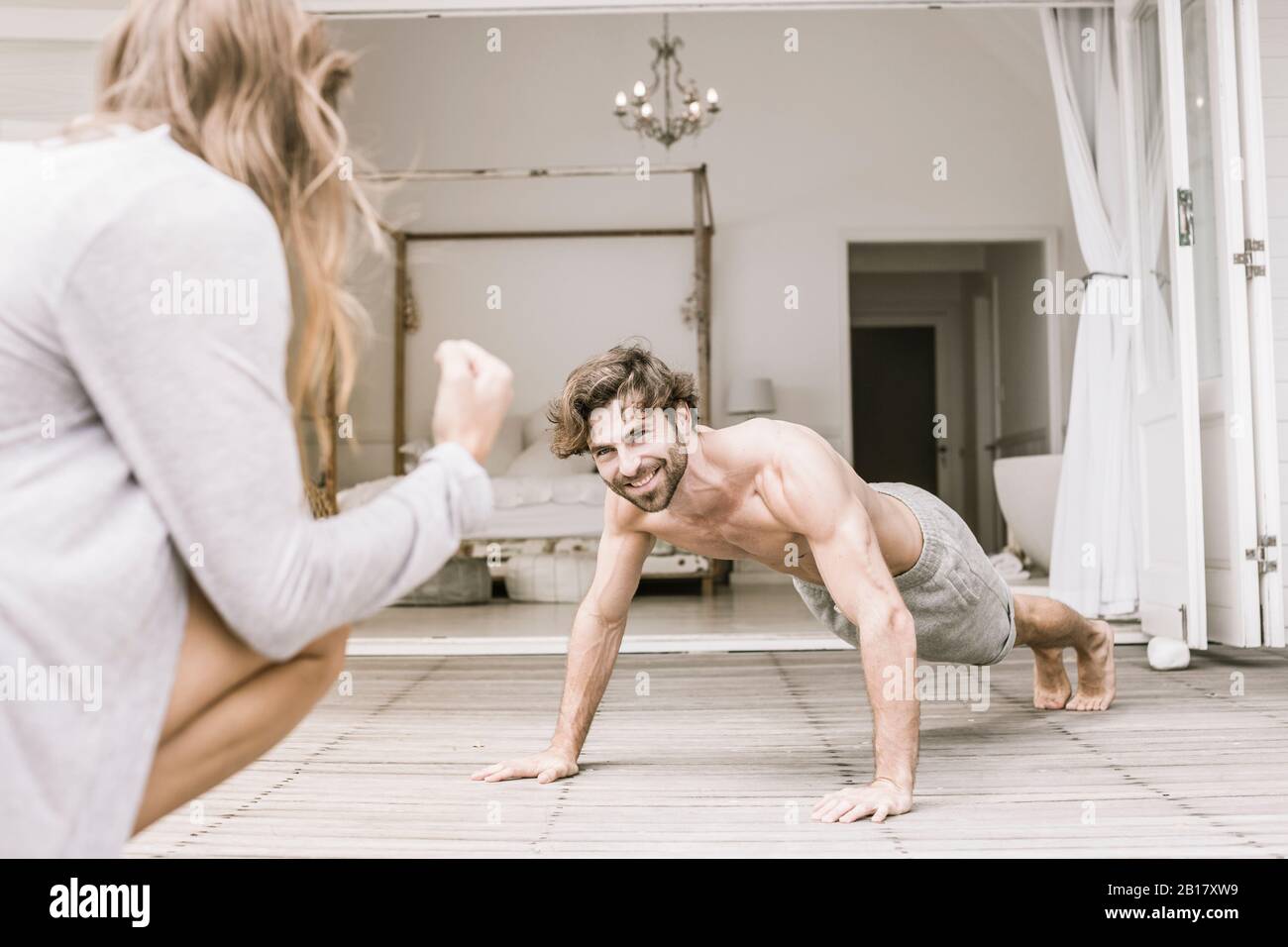 Giovane donna incoraggiante uomo facendo spadup in camera da letto Foto Stock