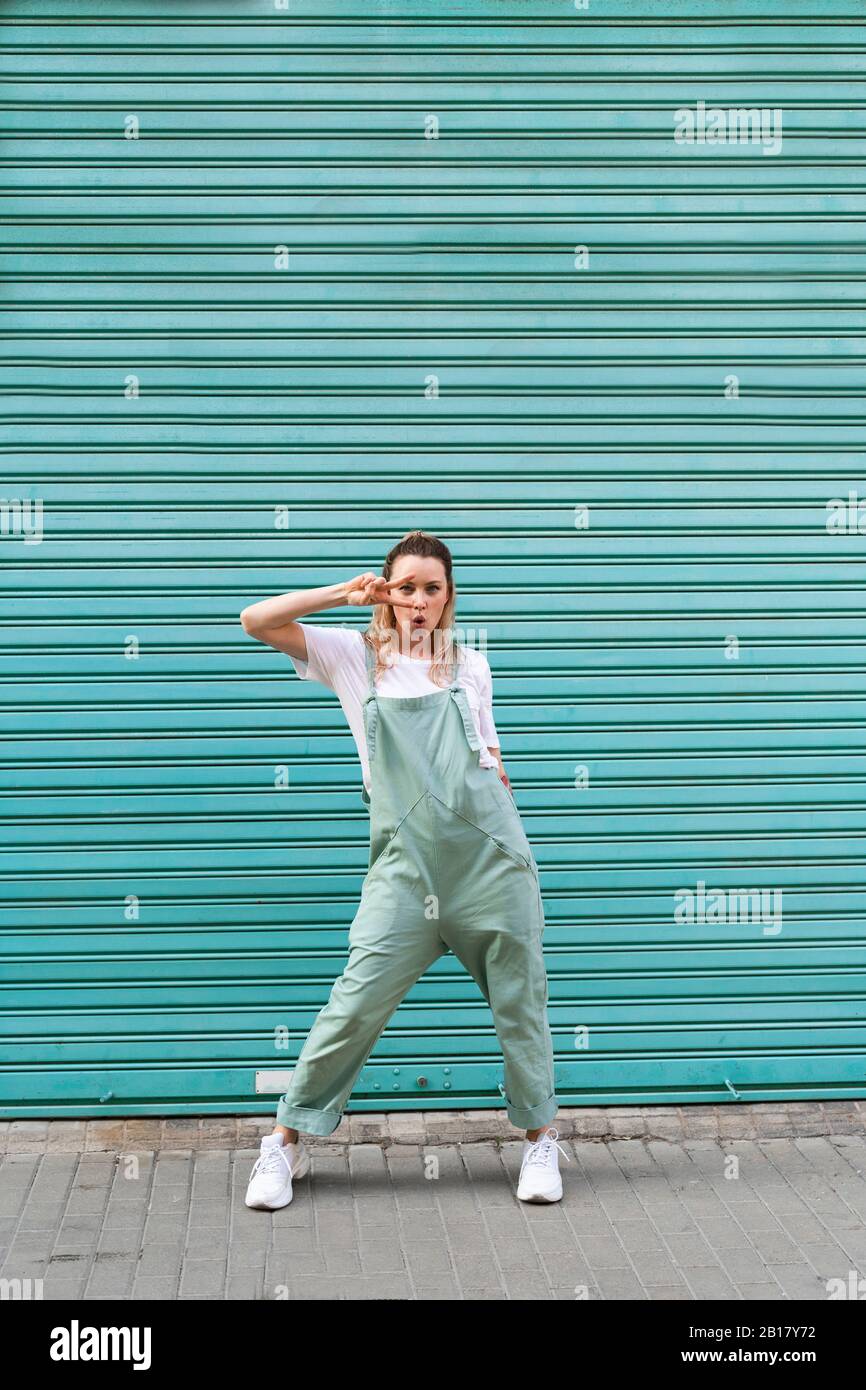 Giovane donna fredda che fa il segno della mano davanti al tapparella blu Foto Stock