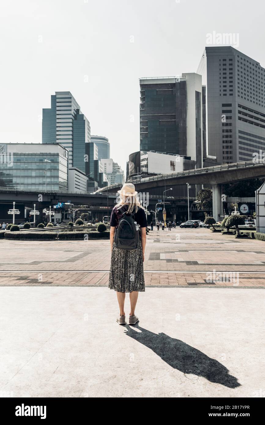 Vista posteriore della donna che guarda agli alti edifici, Bangkok, Thailandia Foto Stock