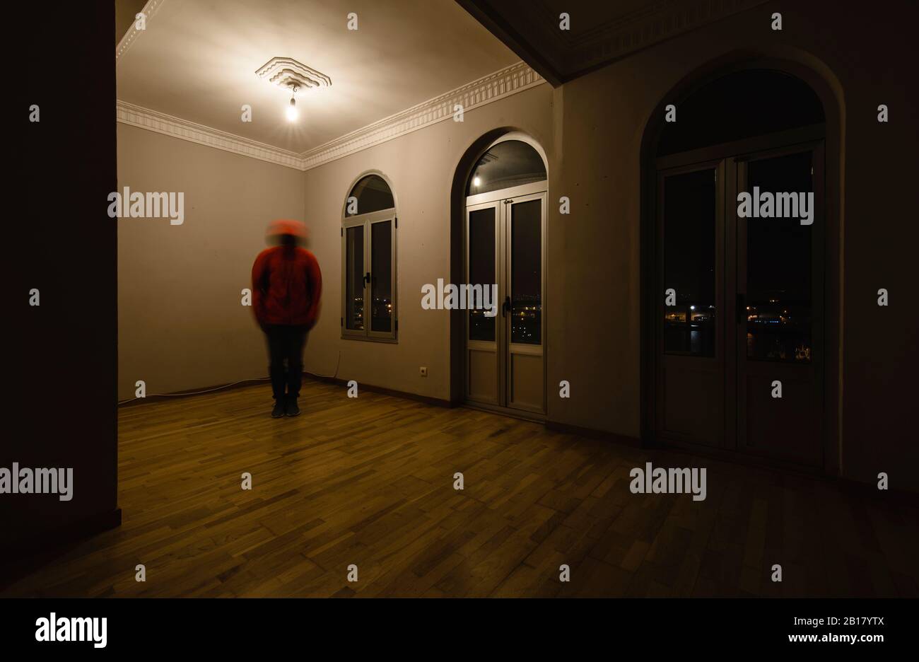 Tremante persona in piedi in stanza vuota di notte Foto Stock