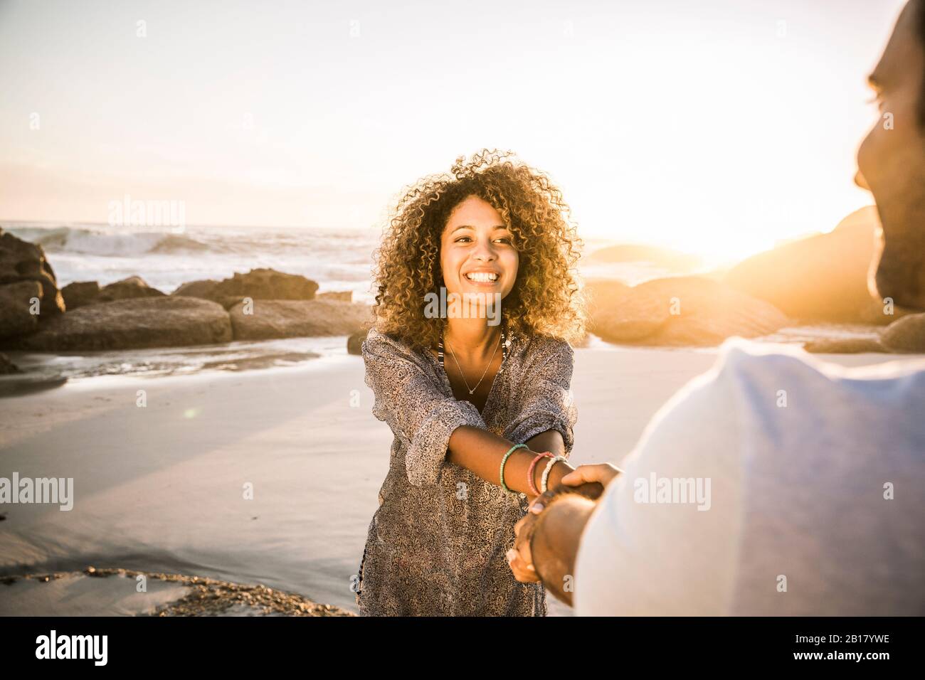 Buona coppia che tiene le mani sulla spiaggia al tramonto Foto Stock