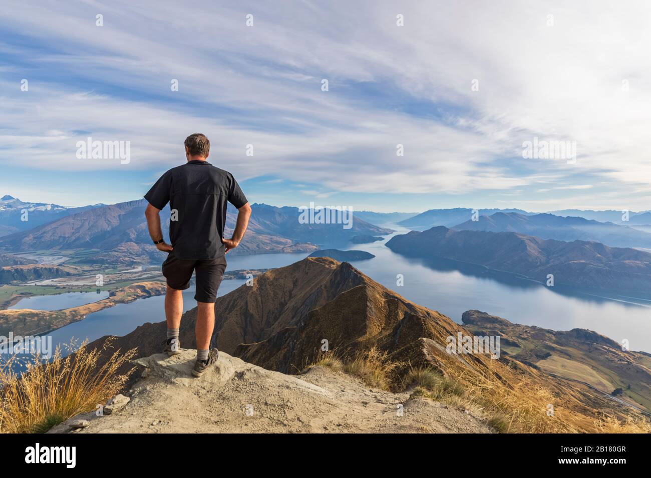 Escursionista in piedi sul punto di vista a Roys Peak, guardando al Monte Aspiring, Lago Wanaka, Isola del Sud, Nuova Zelanda Foto Stock