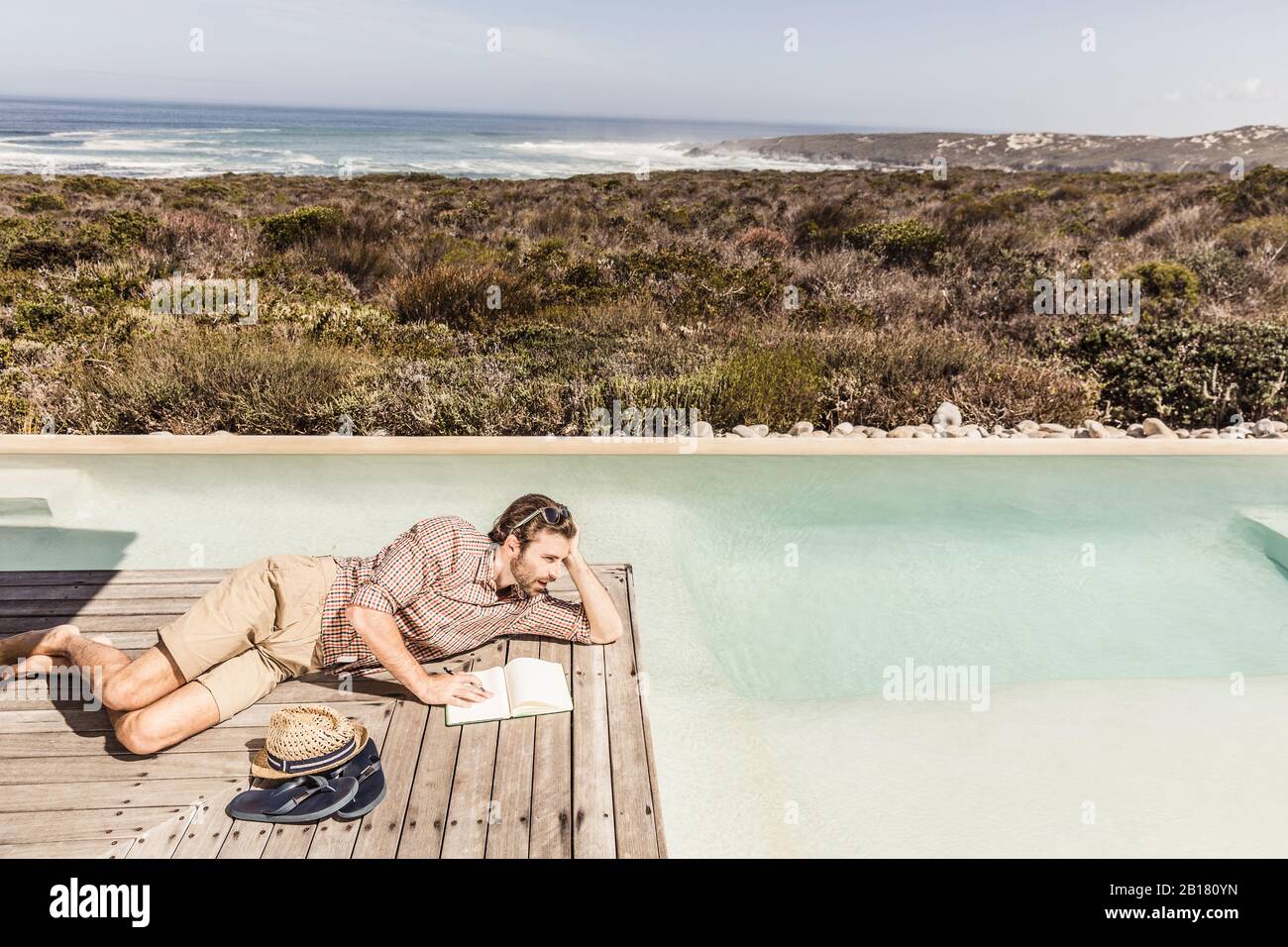 Uomo che si trova accanto a una piscina con un notebook Foto Stock