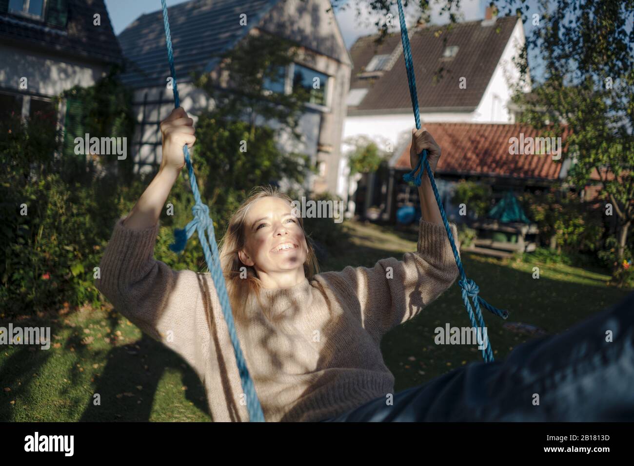 Donna bionda che oscilla nel suo giardino Foto Stock
