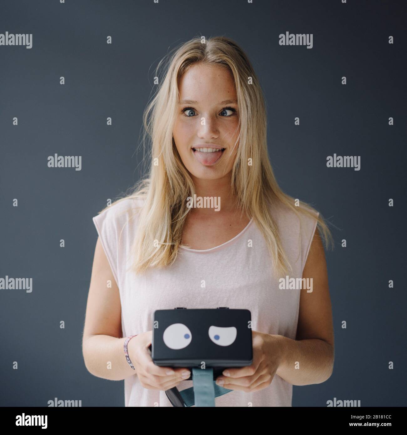 Giovane donna addolorata che tiene occhiali VR con gli occhi dell'unzione Foto Stock