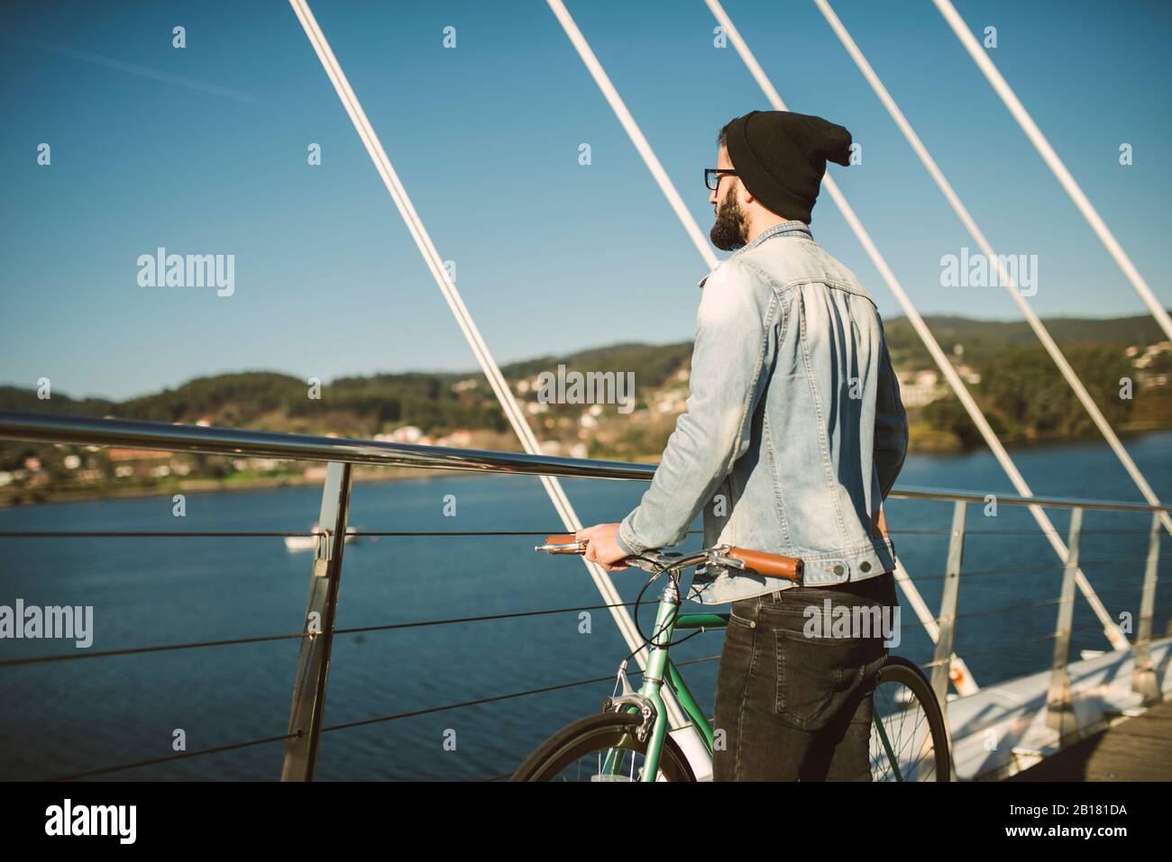 Giovane uomo che si trova in città con la bici Fis fixie, guardando il mare Foto Stock