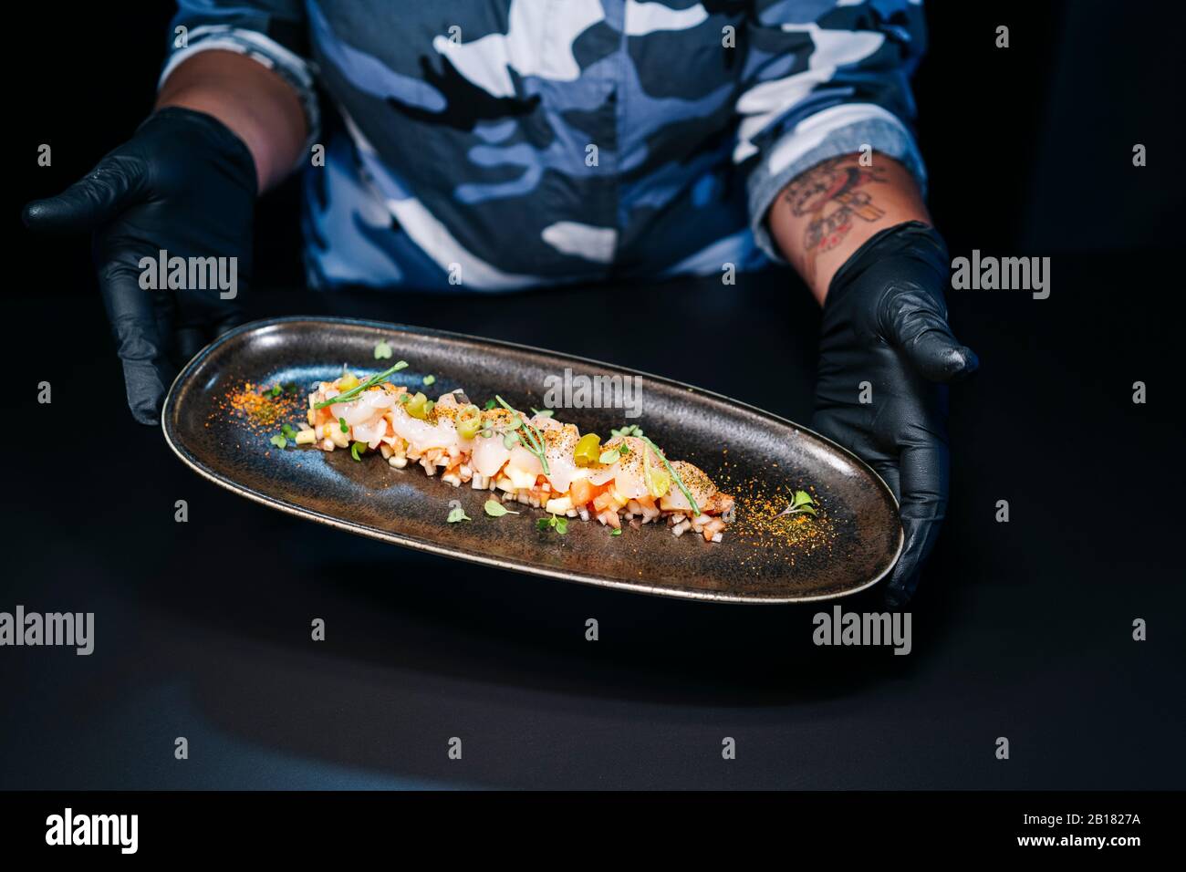 Primo piano dello chef che presenta un piatto nella cucina del ristorante Foto Stock